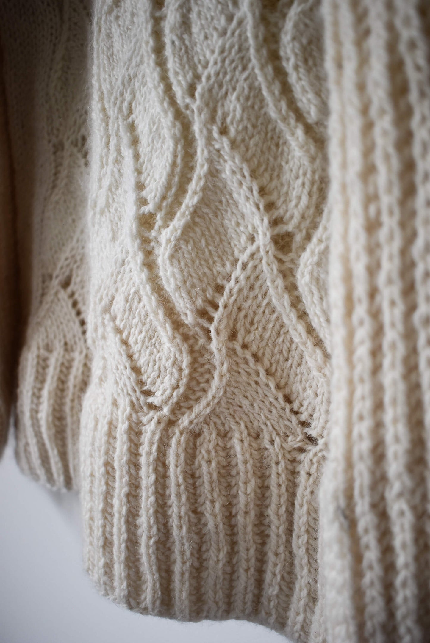 Close-up of a wool knitted fabric with a lace pattern.