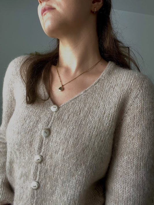 Person wearing a beige sweater with a neutral background