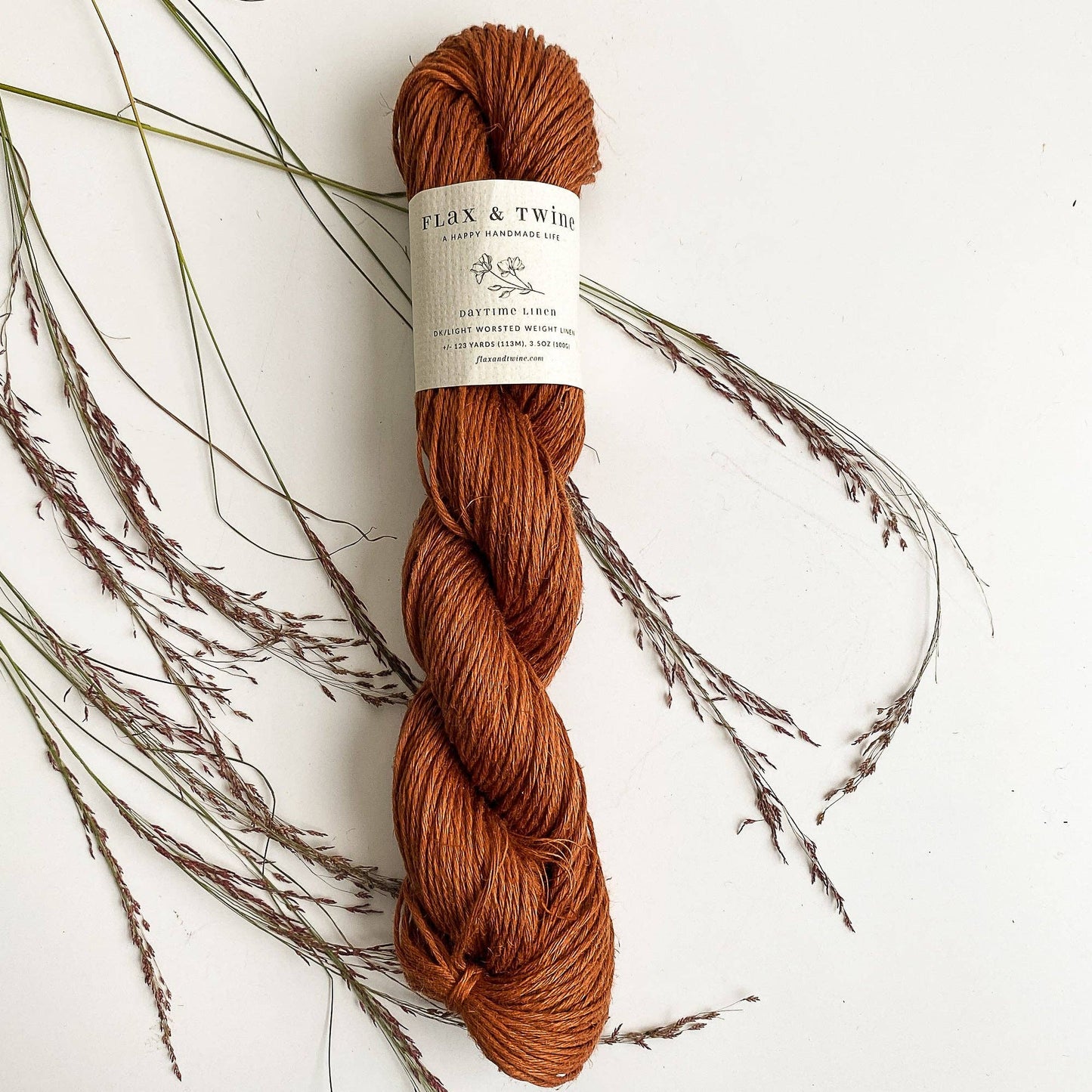 Flax & Twine DK light worsted linen yarn great for summer knitting and crochet, a skein shown in Rust color.