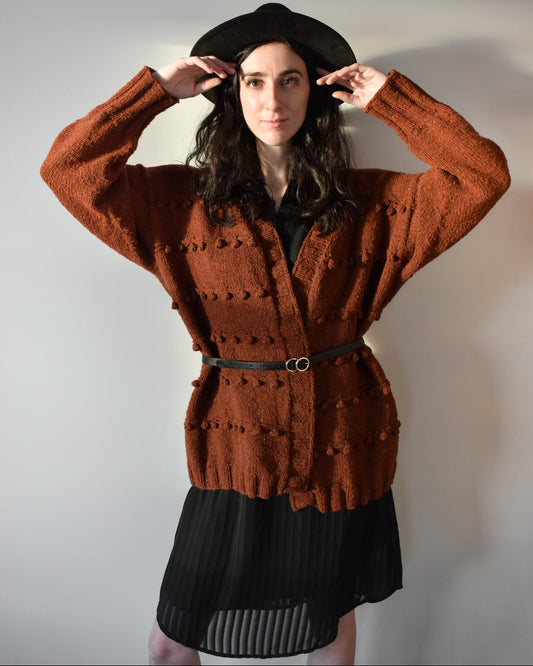 Gooseberry cardigan knitting pattern shown in orange color worn with a belt.