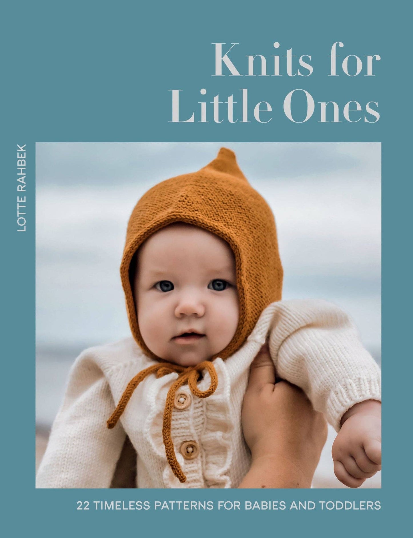 Book cover of Knits for Little Ones with a baby wearing a knitted hat and cardigan.
