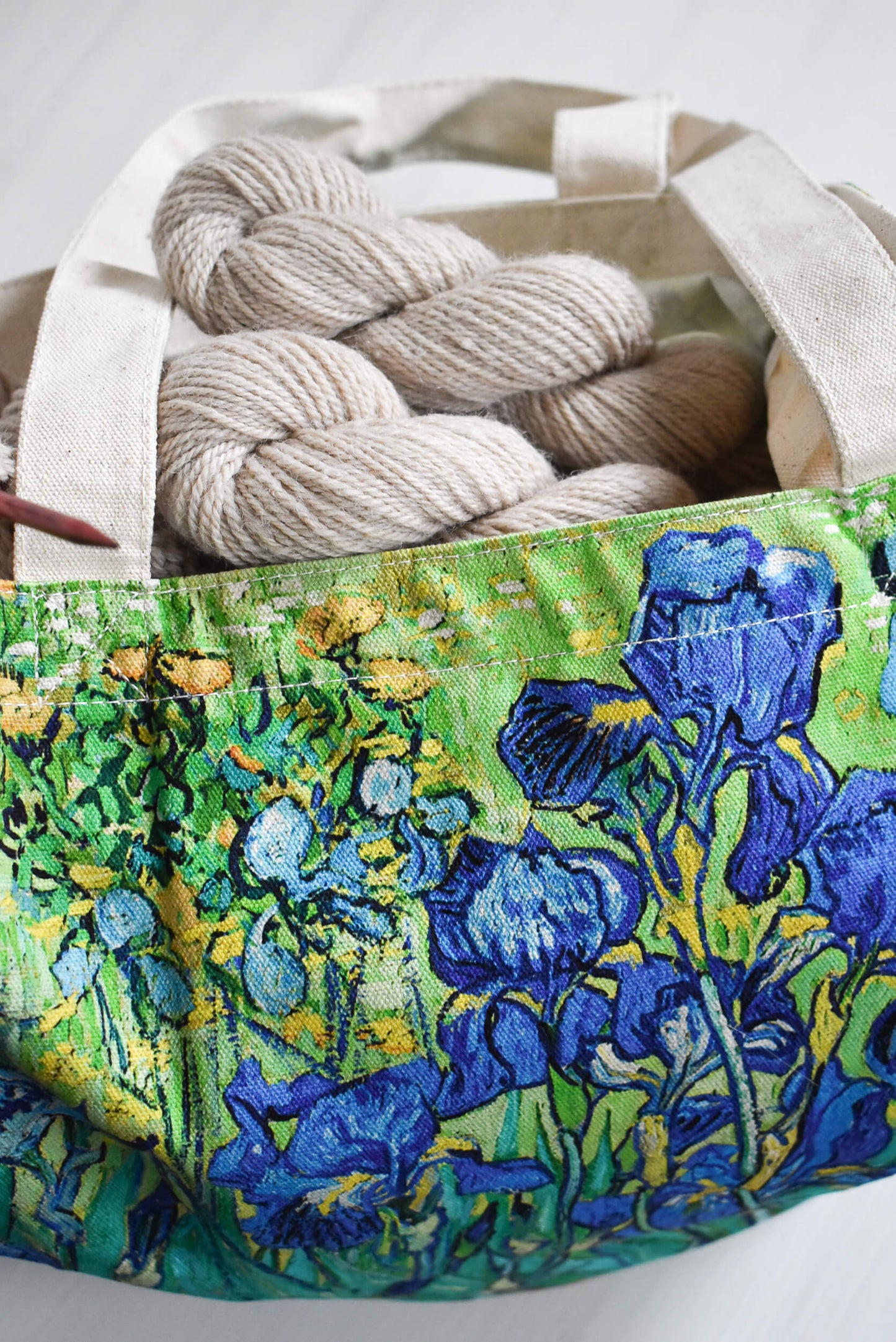 Large tote bag with Van Gogh design filled with yarn and knitting needles.