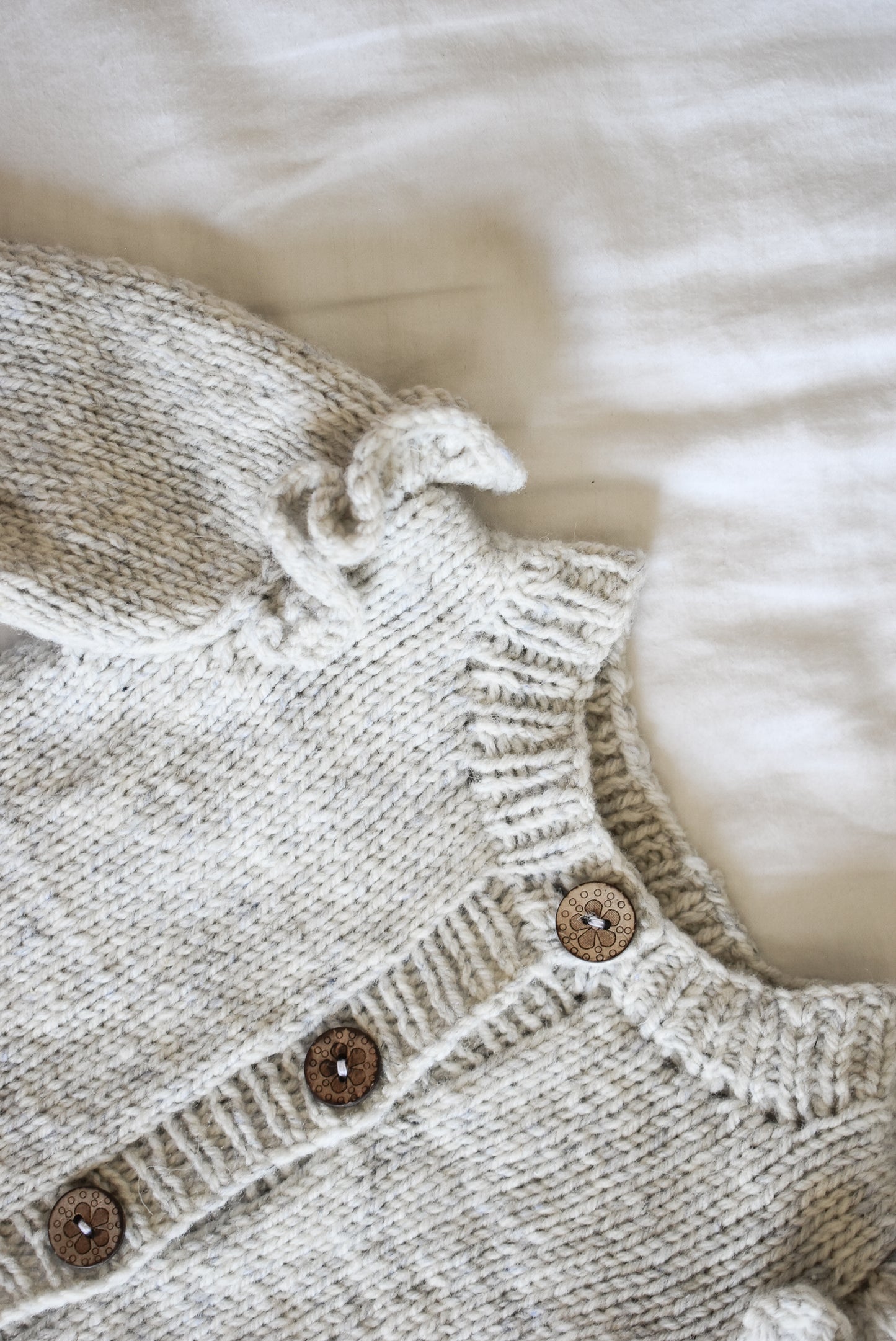 Close-up of the Ruffle Baby Cardigan knitting pattern by Katerina Rieckel from Nest Creative Works.