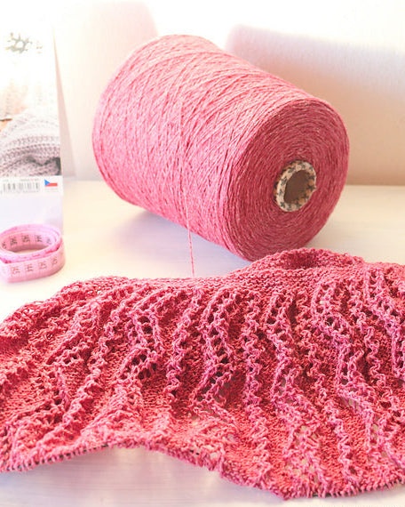 Pink knitted fabric and yarn on a light background.