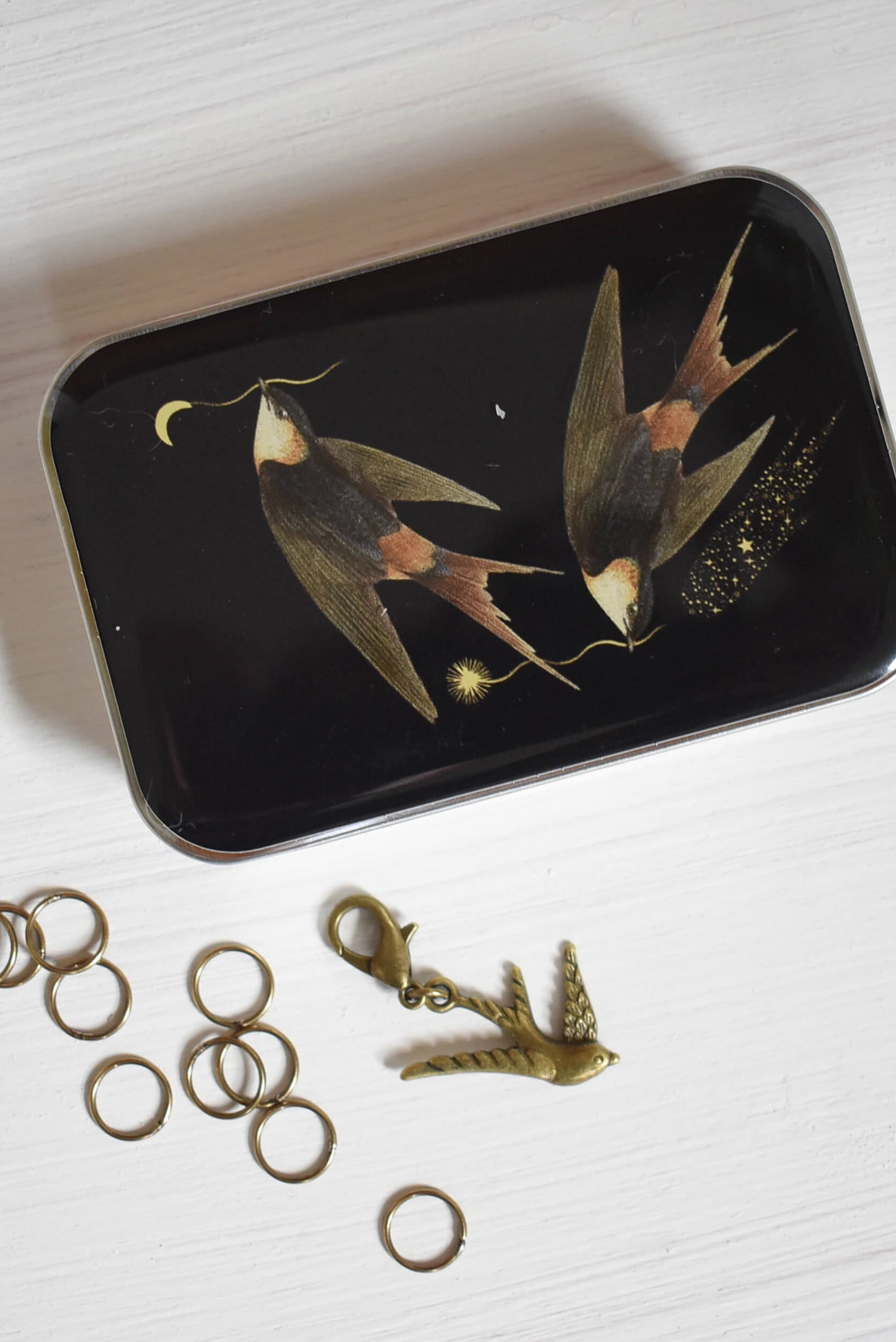 Knitting notions tin with a bird design, 10 round stitch markers and one bird progress keeper for knitting.