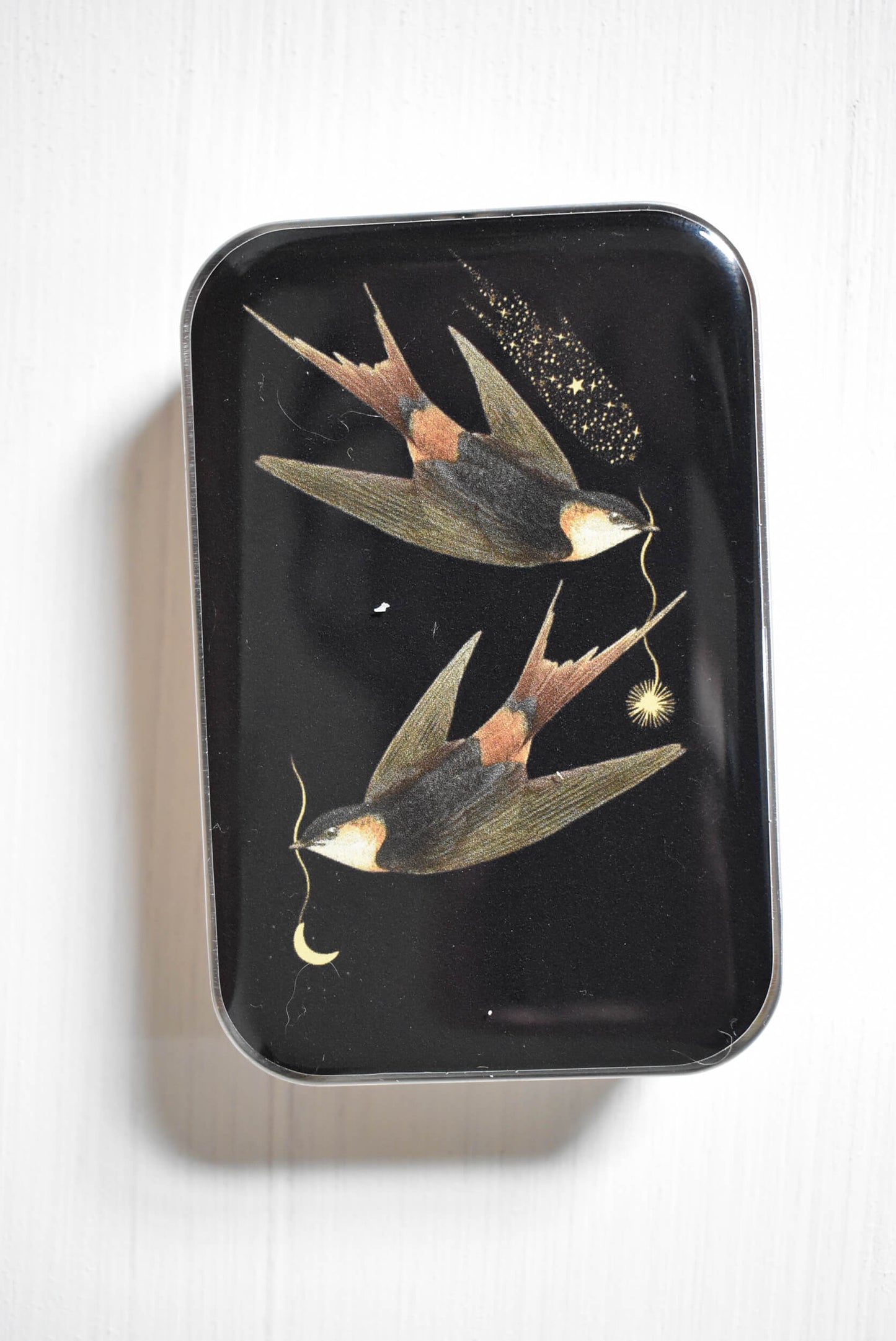 Celestial swallows knitting notions tin with stitch markers and a progress keeper.