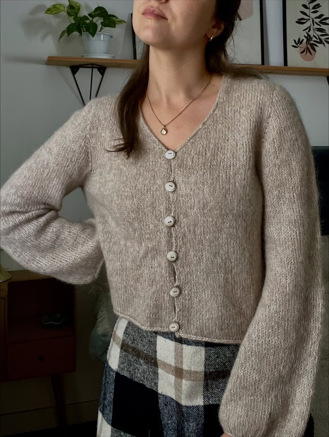 Photo of a woman wearing a beige hand-knitted cardigan based on the Cloud Cardigan knitting pattern.