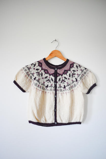 Knitted sweater with a floral pattern featuring birds and botanical motifs.