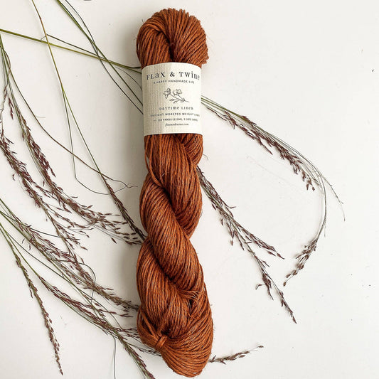 Flax & Twine DK light worsted linen yarn great for summer knitting and crochet, a skein shown in Rust color.