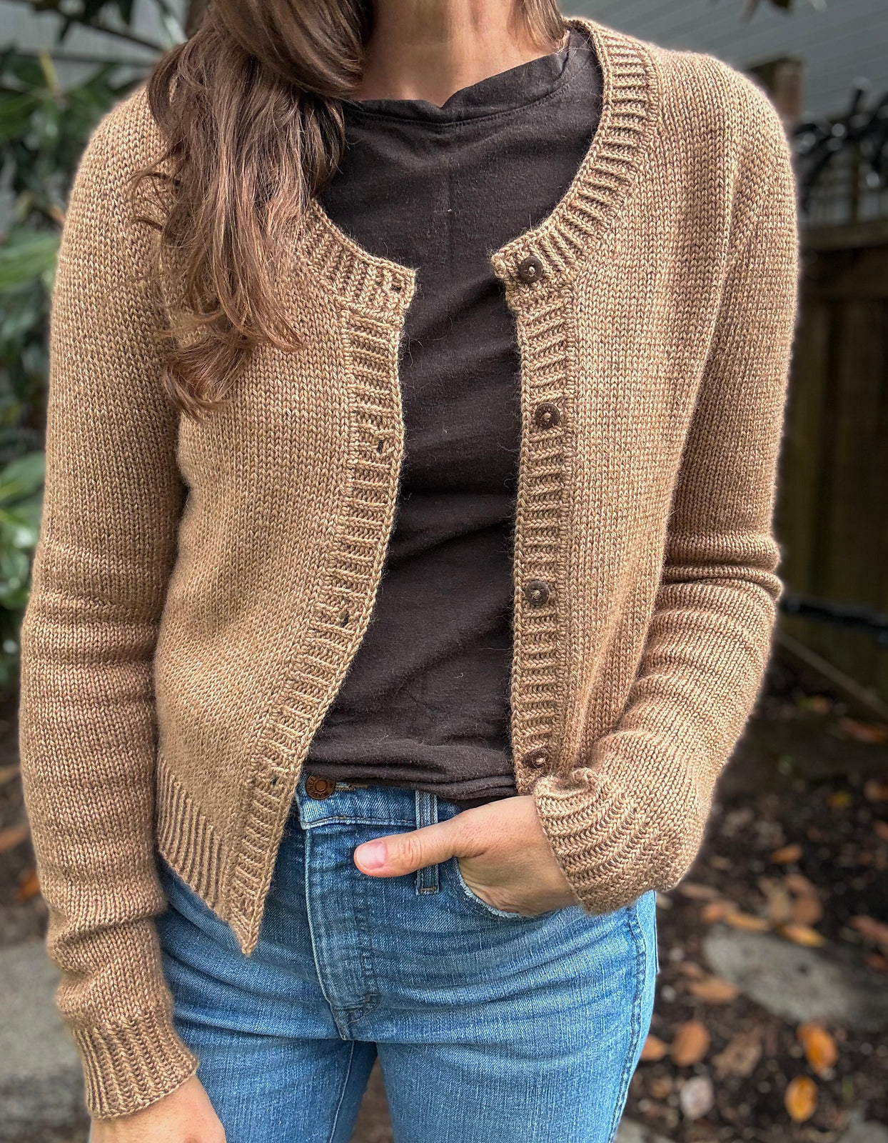 Jacqui wearing a brown knitted Deepwood cardigan over a dark shirt with blue jeans.