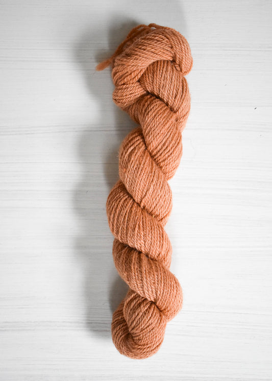Peach-colored baby alpaca wool yarn skein.