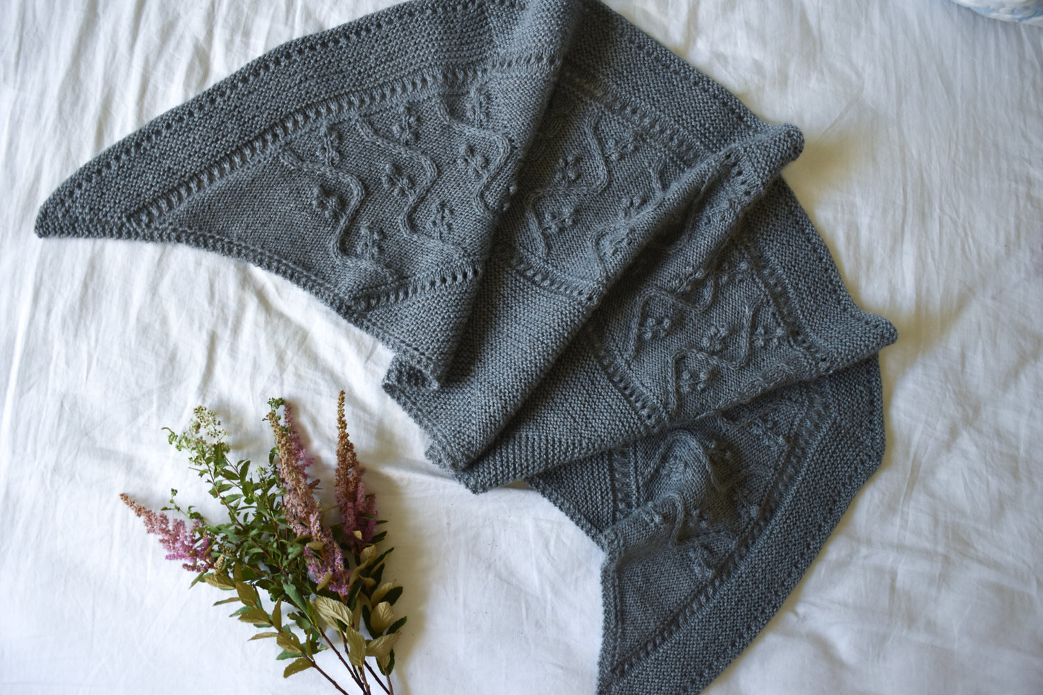 Gray-blue knitted shawl on a white background based on the Lady of the Lake shawl knitting pattern.
