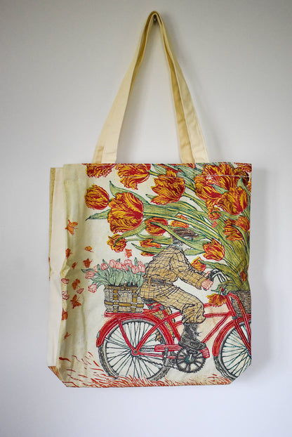 Tote bag with a design of a person on a bicycle with tulips.