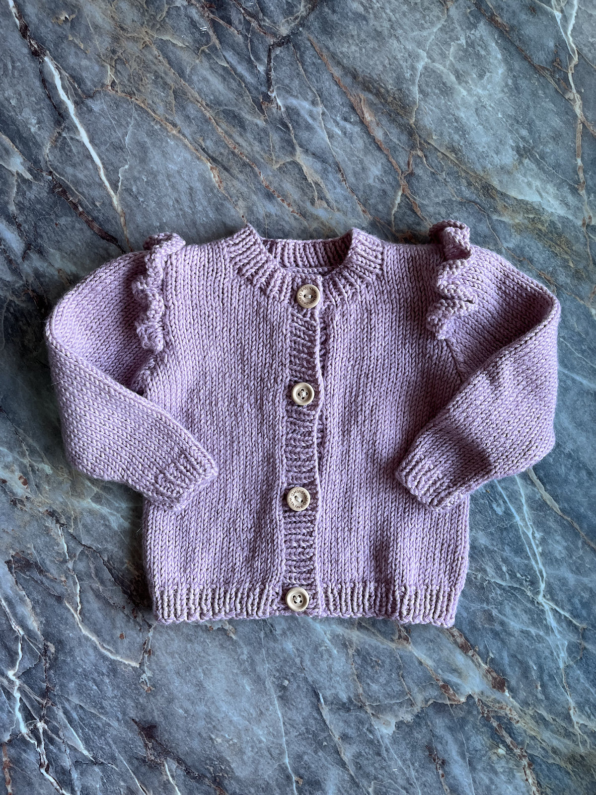 Ruffle baby cardigan knitting pattern in pink color, knitted by  Knotmadmaddie.