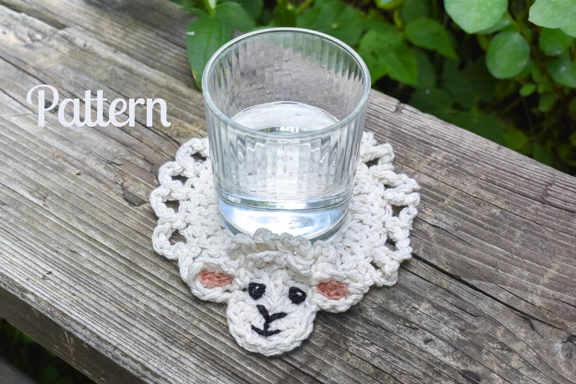 Photo of a crochet lamb coaster pattern, showing the finished coaster with a glass of water on a wooden surface.