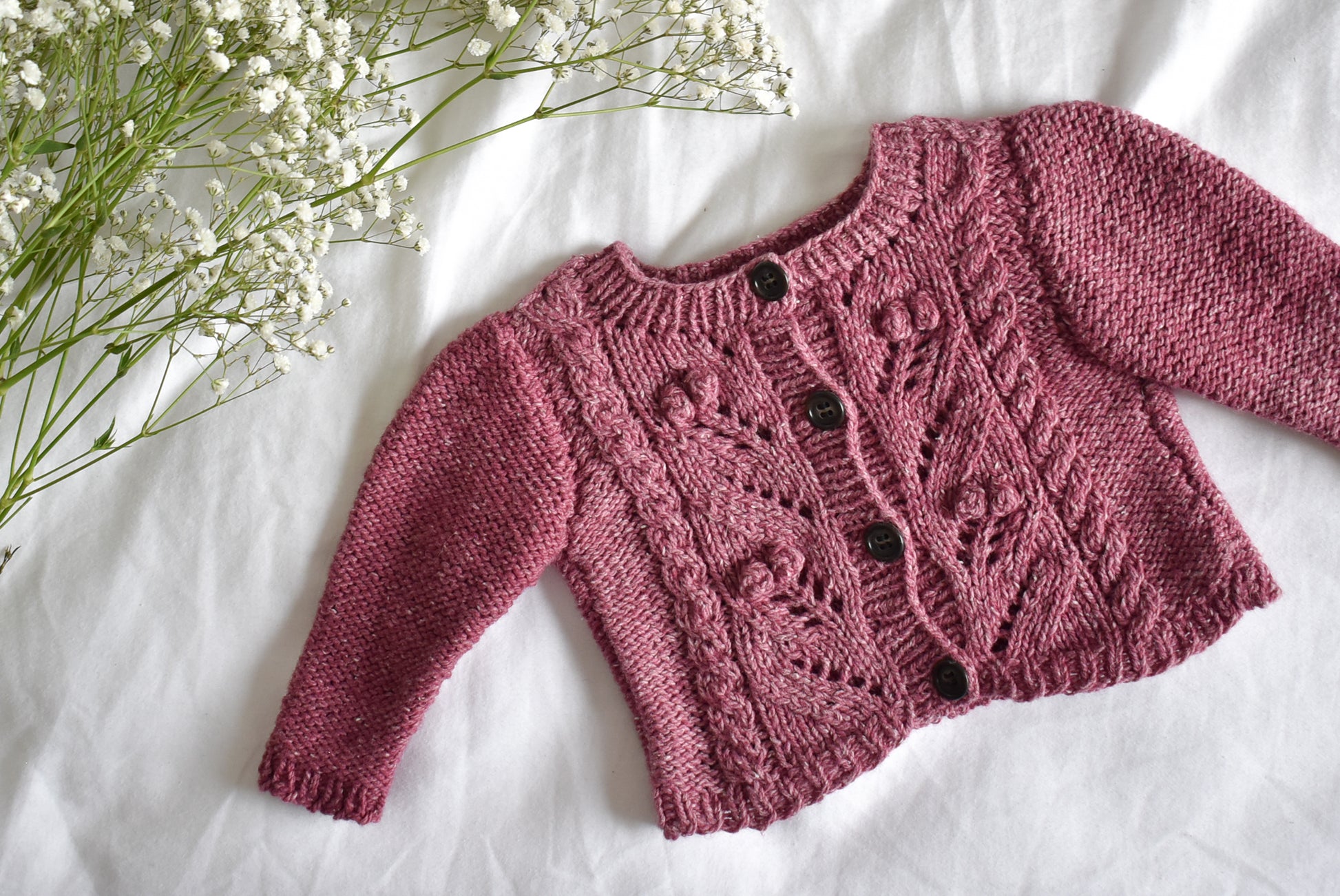 Image showing Sofie's Cardigan Baby Knitting pattern project laid flat on a white sheet.