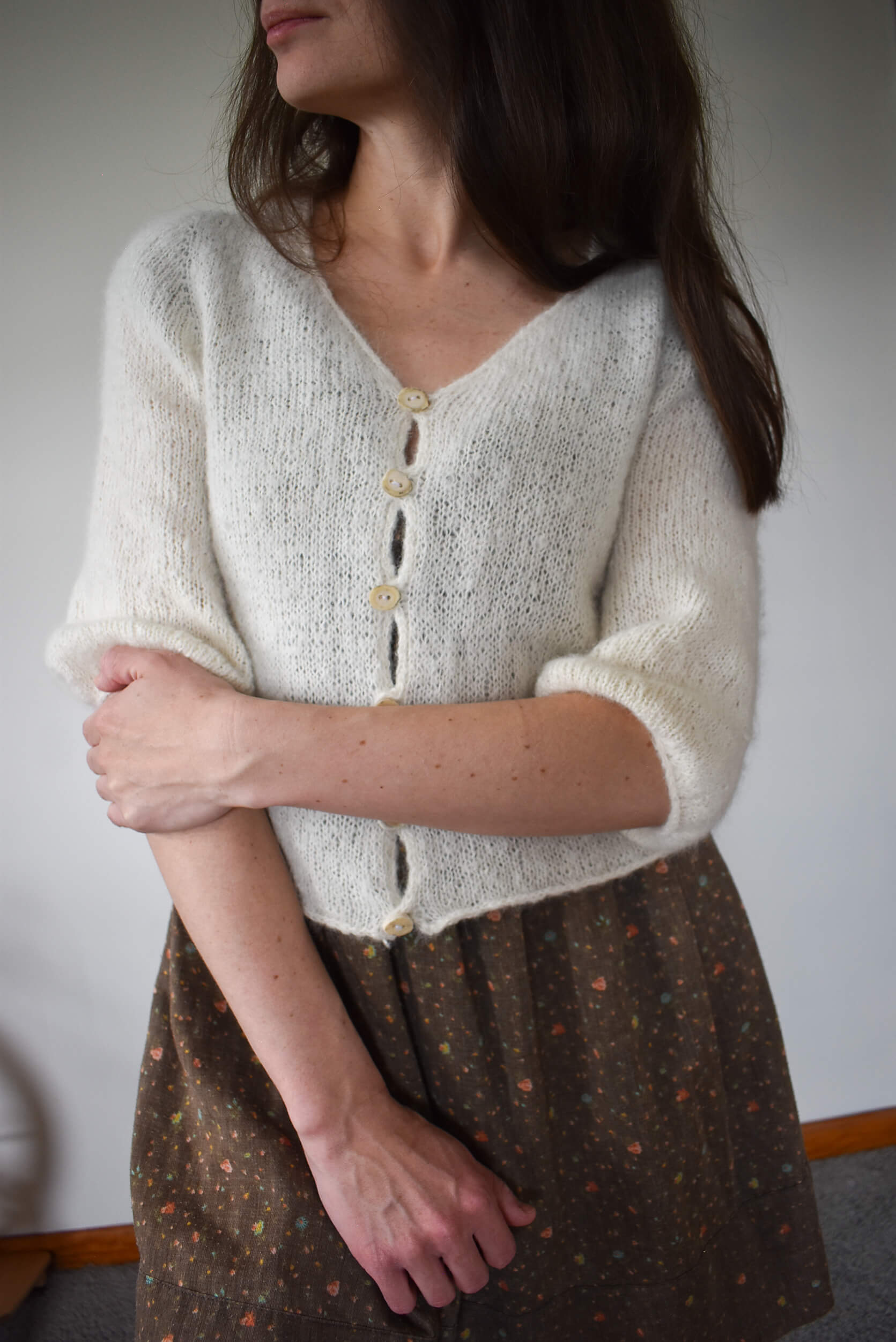 Suri alpaca knitted cardigan over a brown patterned skirt.