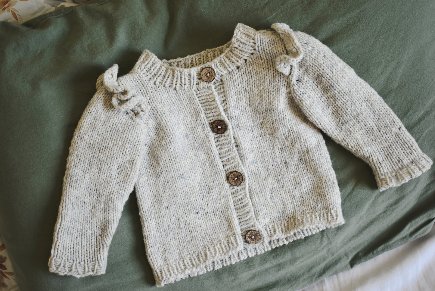 Cute baby cardigan knitting pattern with ruffles designed by Katerina Rieckel.